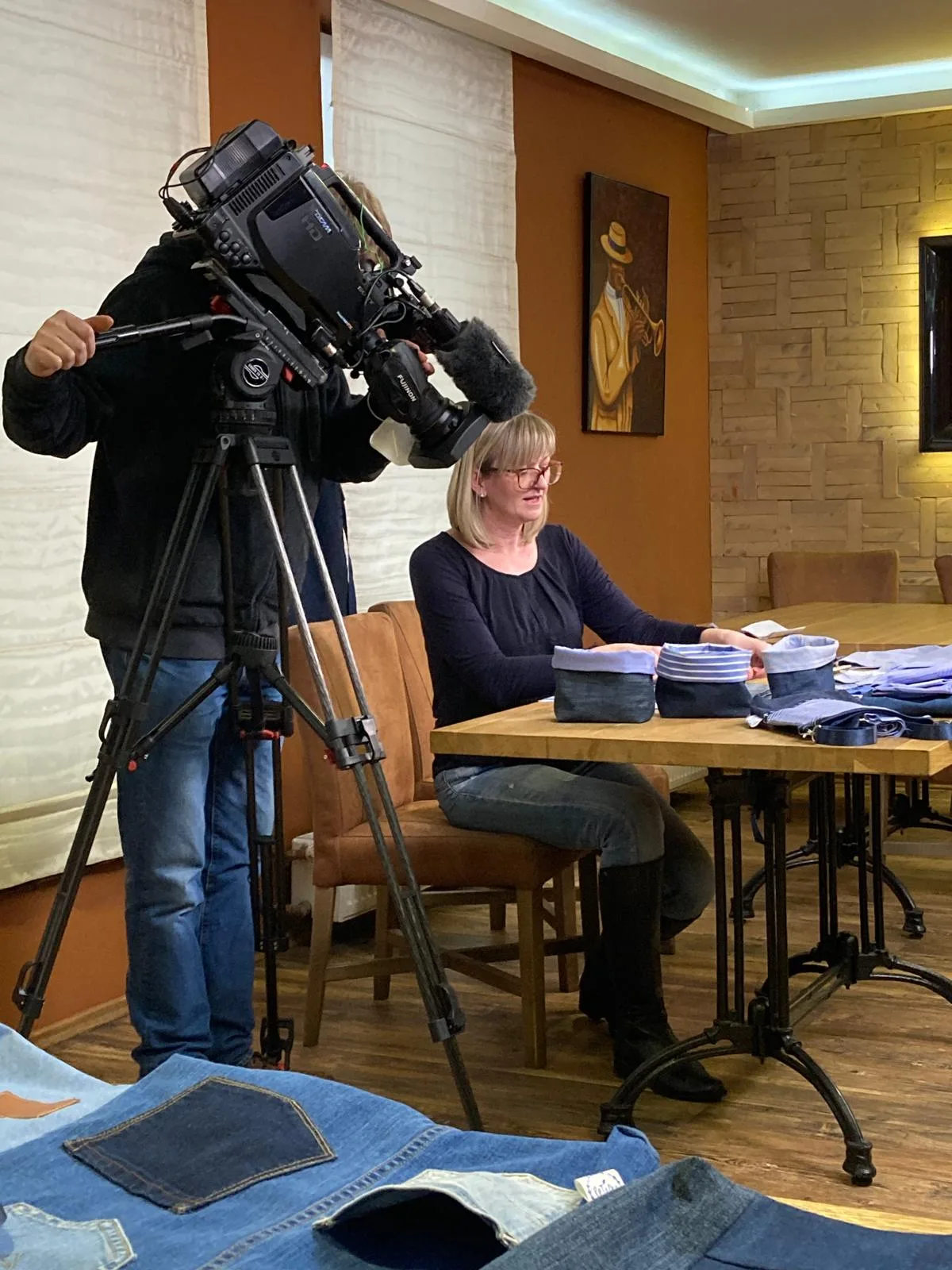 Kameraman České televize natáčí Markétu u stolu s košíky z riflí